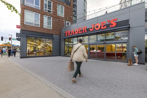 a man walking down a sidewalk in front of a trader joes store