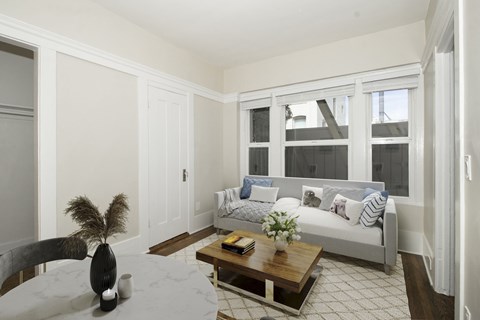 A living room with a couch, coffee table, and a vase on the table.