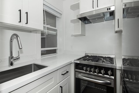 A modern kitchen with a stove, sink, and cabinets.