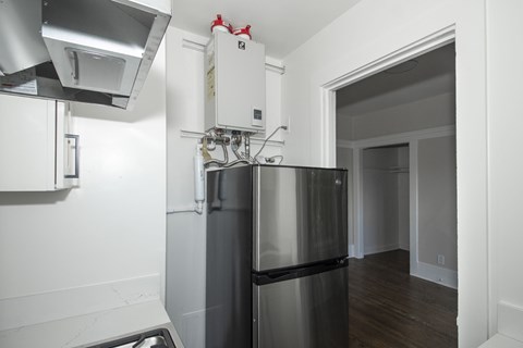 A kitchen with a stainless steel refrigerator and a white wall.