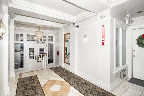 A hallway with a chandelier, a door, and a wreath on the door.