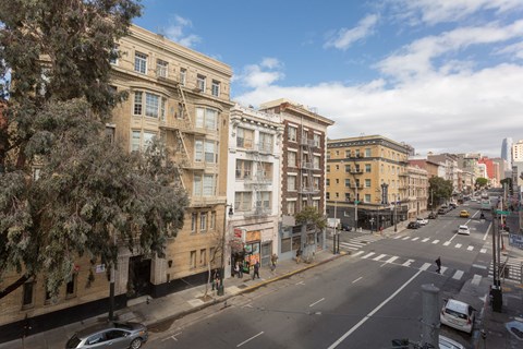 A street view of a city with buildings on both sides and cars on the road.