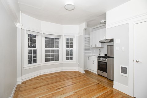 A kitchen with white cabinets and a wooden floor.