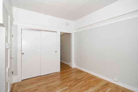 A room with white walls and wooden flooring with two white doors.