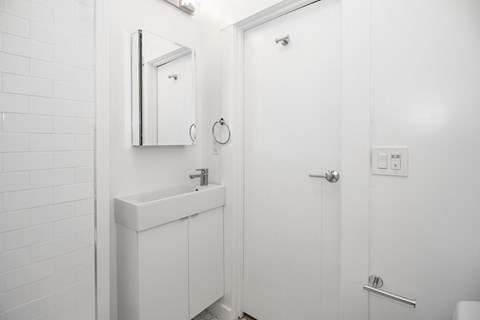 A white bathroom with a sink and mirror.