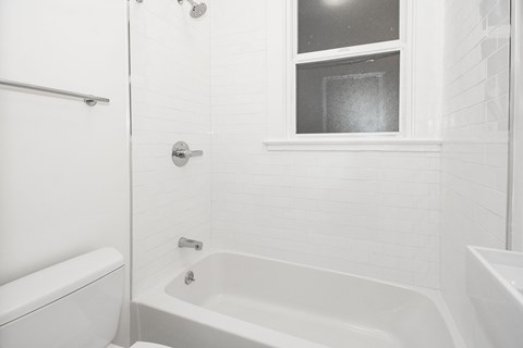 A white bathroom with a tub, toilet, and sink.