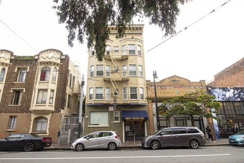 A street view of a row of buildings with cars parked in front.
