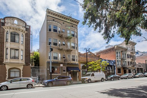 A street view of a row of buildings with cars parked on the side of the road.