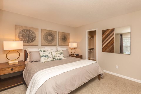 A bedroom with a large bed and two wall art pieces.