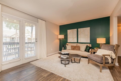 A living room with a couch, armchair, and a table with a lamp on it.