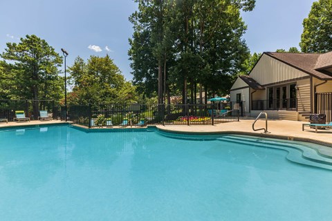 A large swimming pool surrounded by trees and a building.