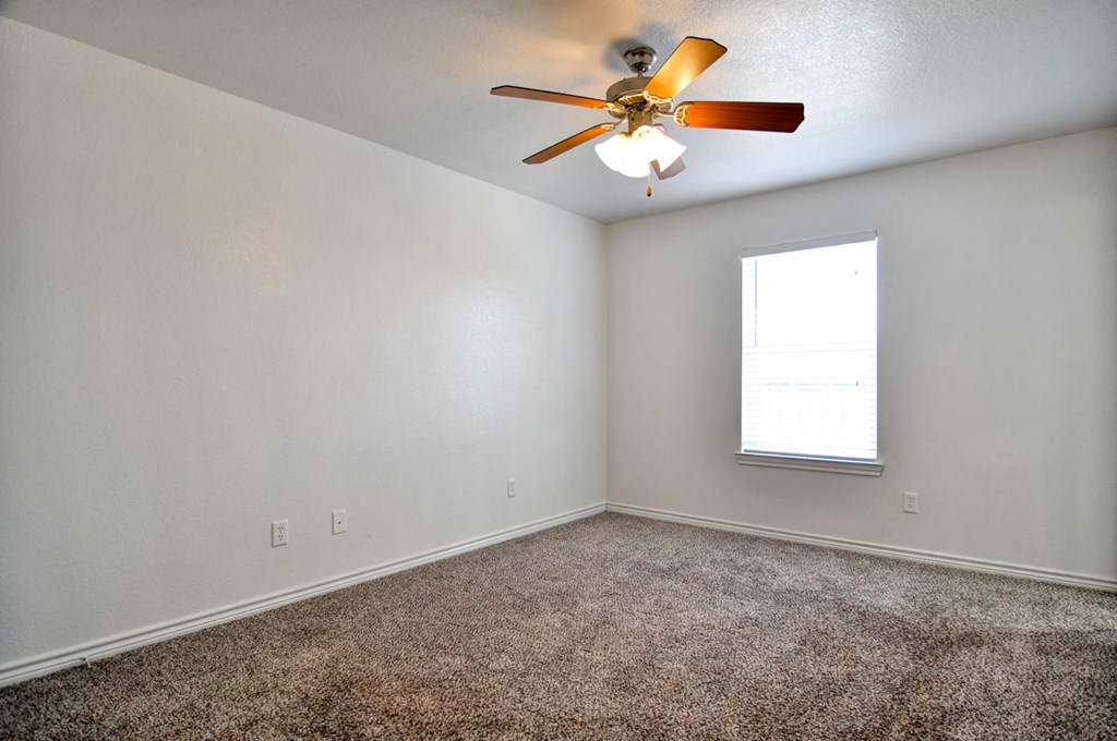 an empty room with a ceiling fan and a window