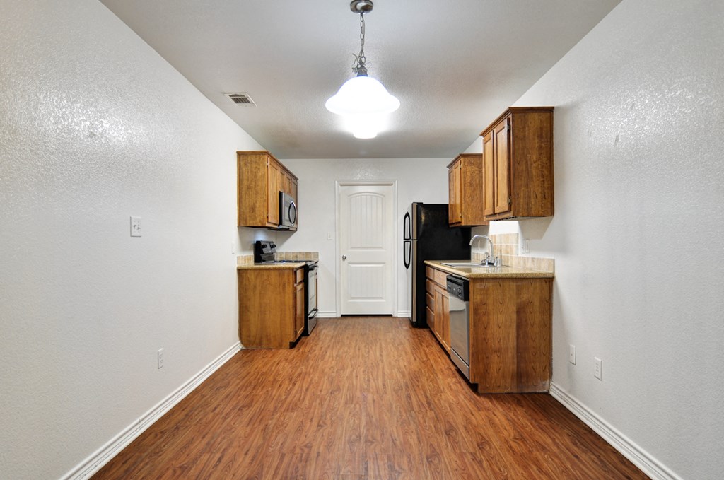 an empty kitchen with wood flooring and wooden cabinets