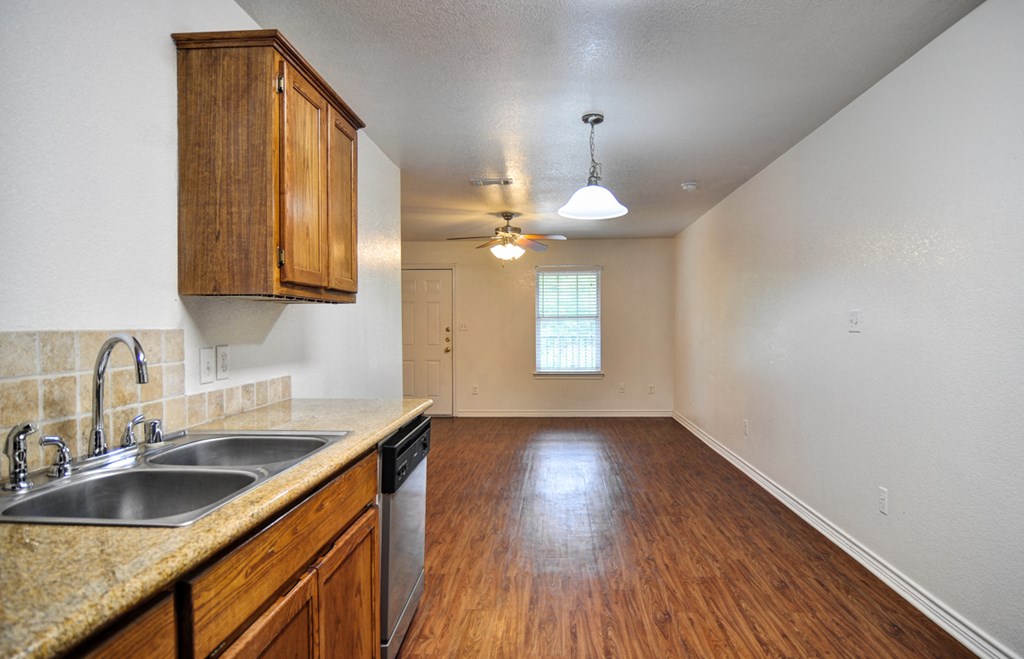 an empty kitchen and living room with wood flooring and a sink