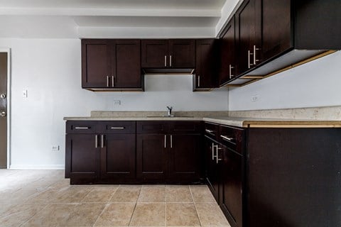 an empty kitchen with wooden cabinets and tile floors