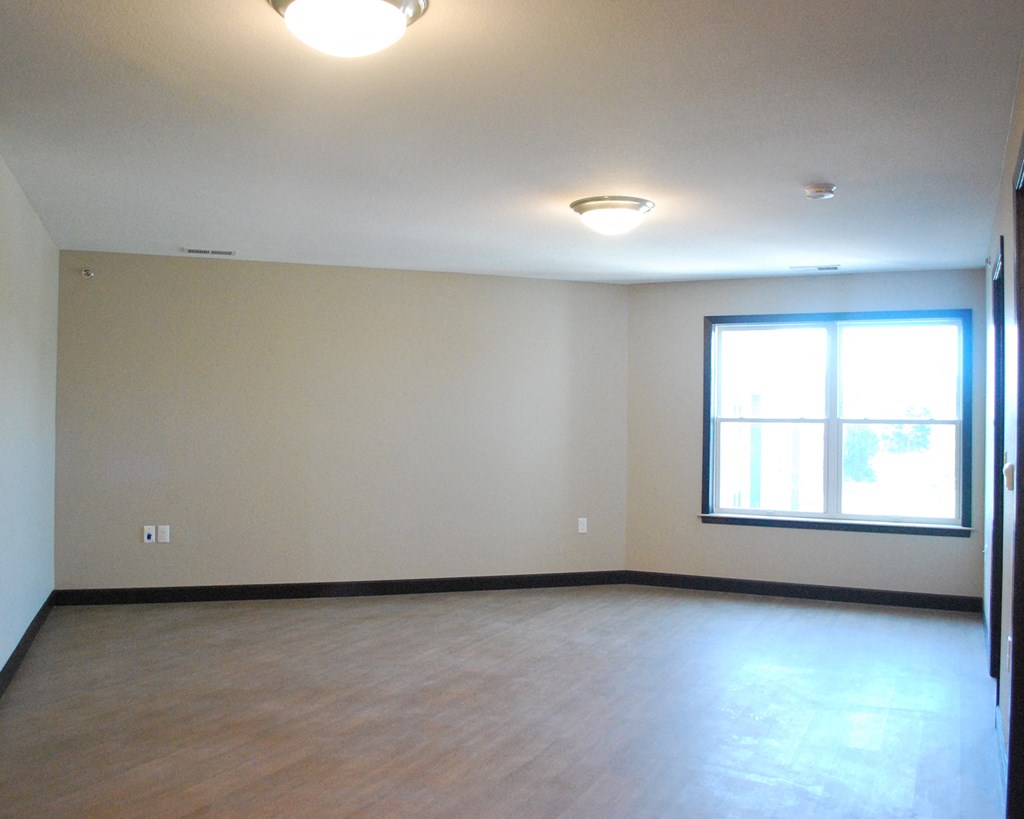an empty living room with a window and wood floors