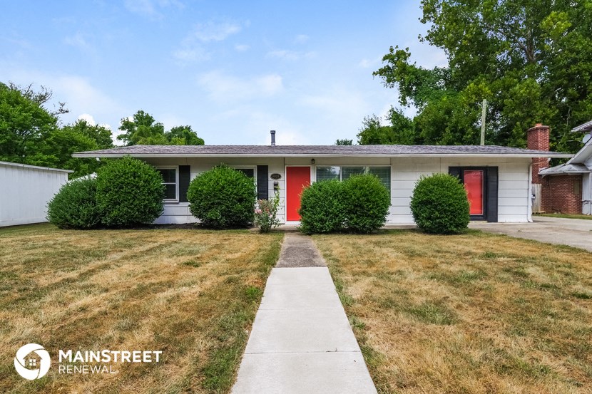 a small white house with red doors and a sidewalk