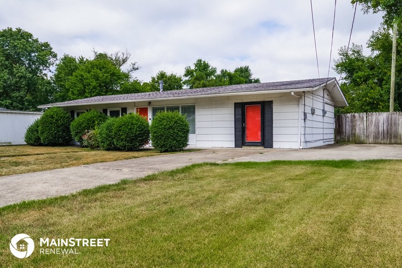 a small white house with a red door and a lawn