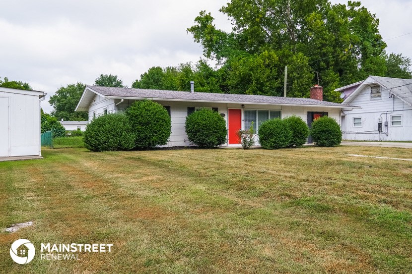 a white house with a yard and a red door