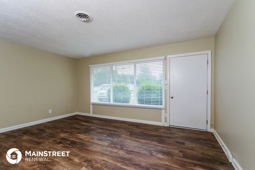 the living room of an apartment with wood flooring and a window