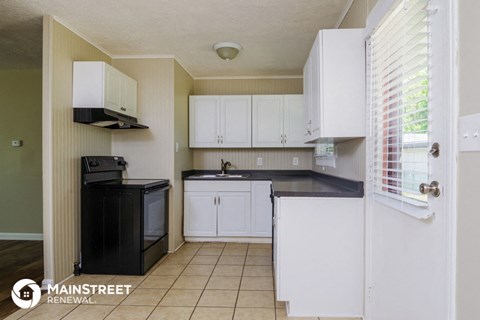 a kitchen with white cabinets and black counter tops and a black stove and refrigerator