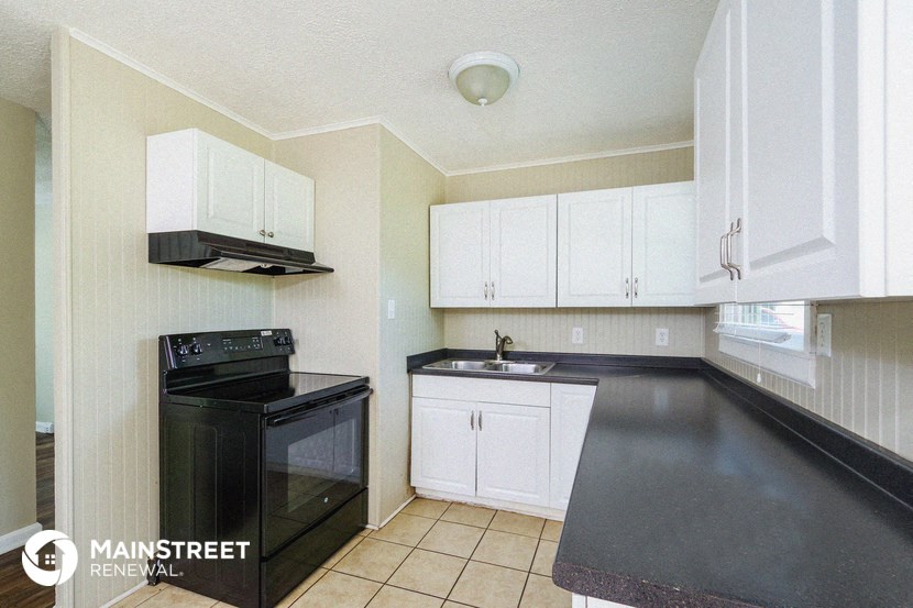 a kitchen with white cabinets and black counter tops and a black stove top oven
