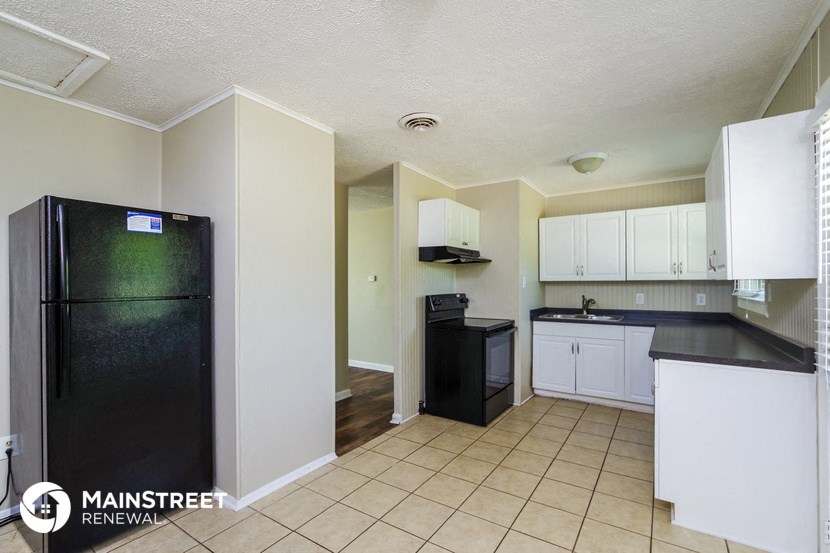 a kitchen with a black refrigerator and white cabinets