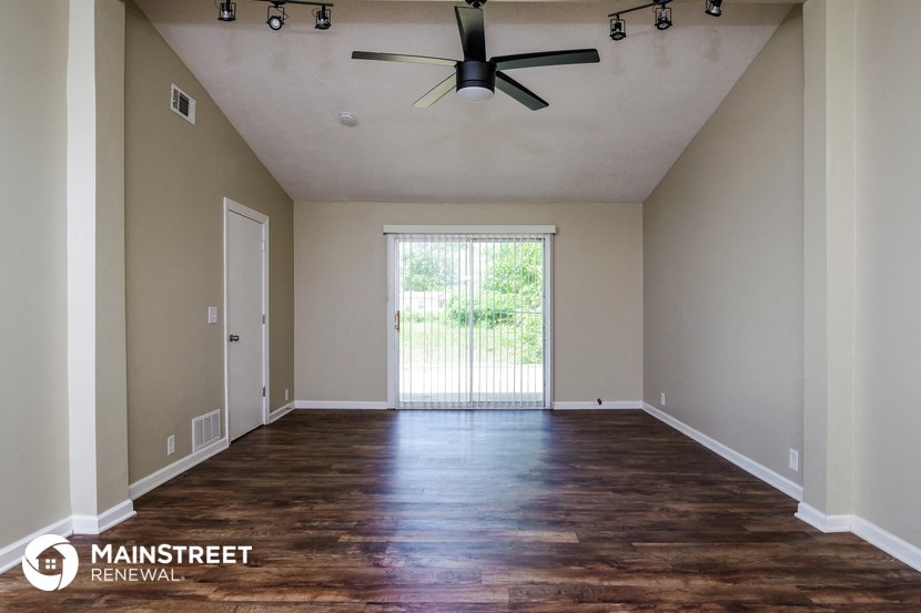 an empty living room with wood floors and a ceiling fan