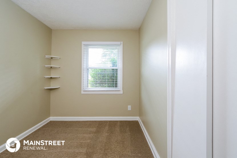 an empty room with a window and white shelves