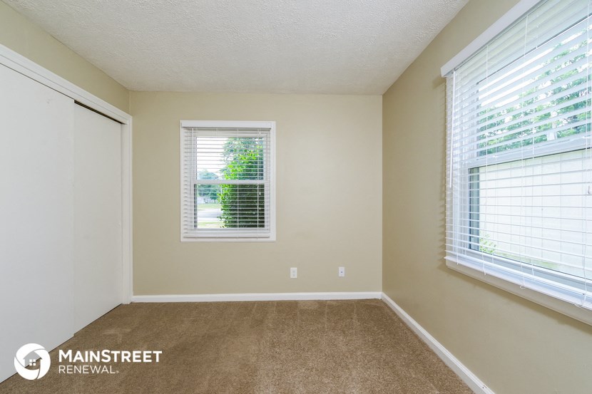 a bedroom with a carpeted floor and two windows