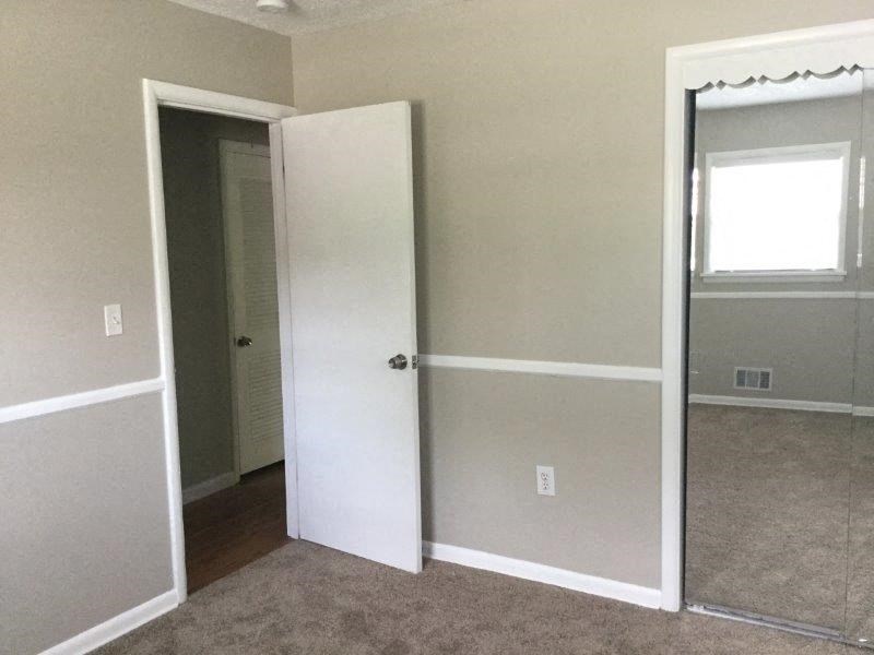 an empty room with an open door and a mirror