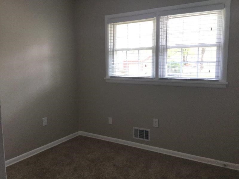 an empty room with a window and a carpet