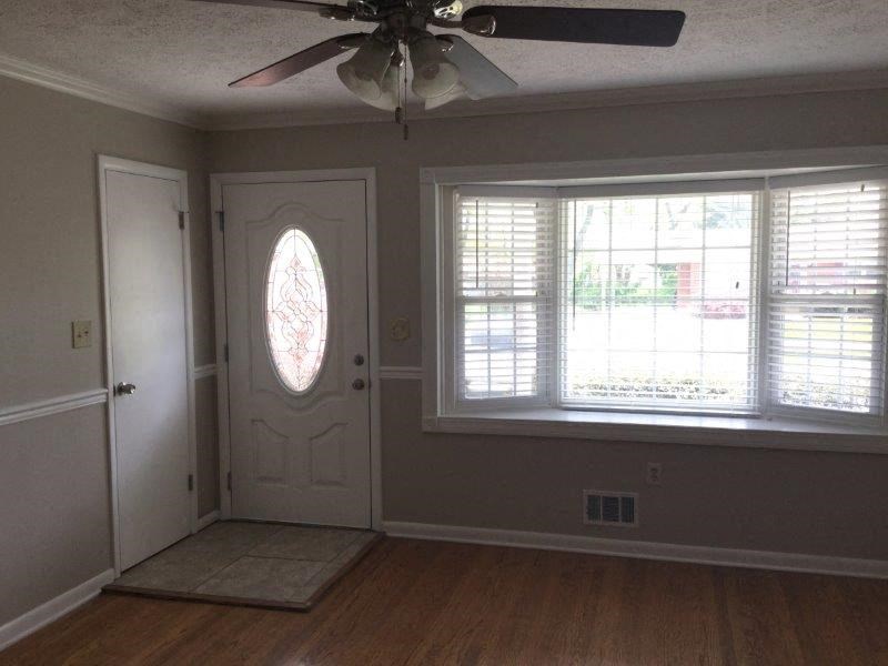 an empty living room with a ceiling fan and a window