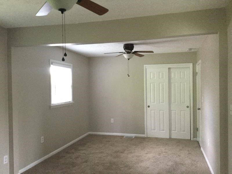 an empty living room with a ceiling fan and a door