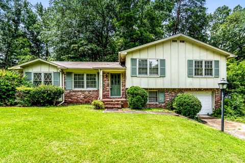 a white house with green shutters and a green lawn