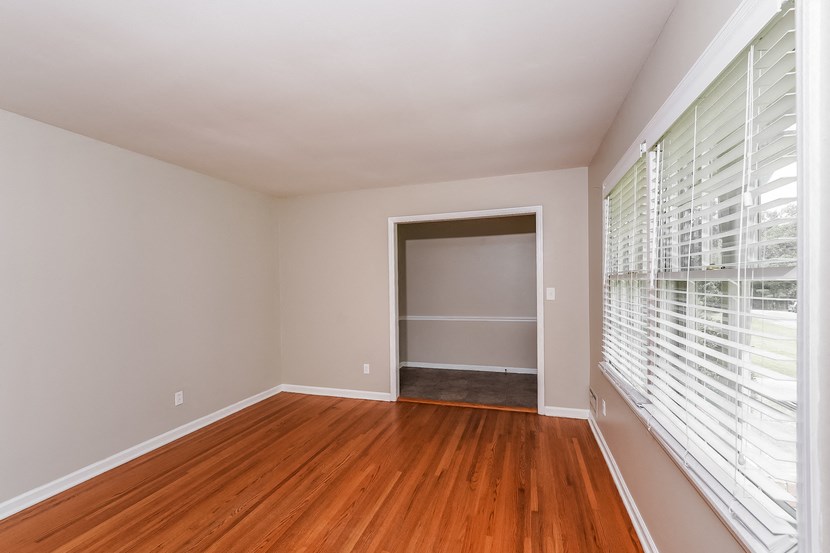 an empty room with wood floors and a large window