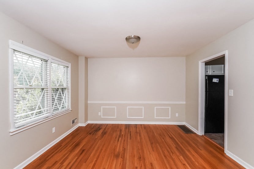 an empty living room with wood floors and a large window