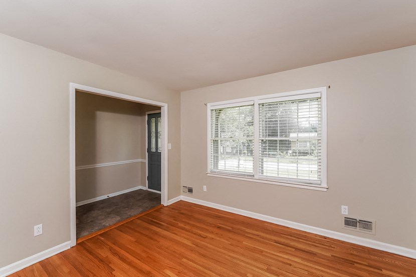 an empty living room with wood floors and a large window
