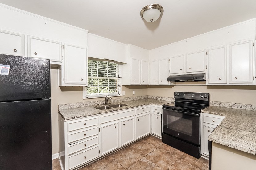 a kitchen with white cabinets and black appliances