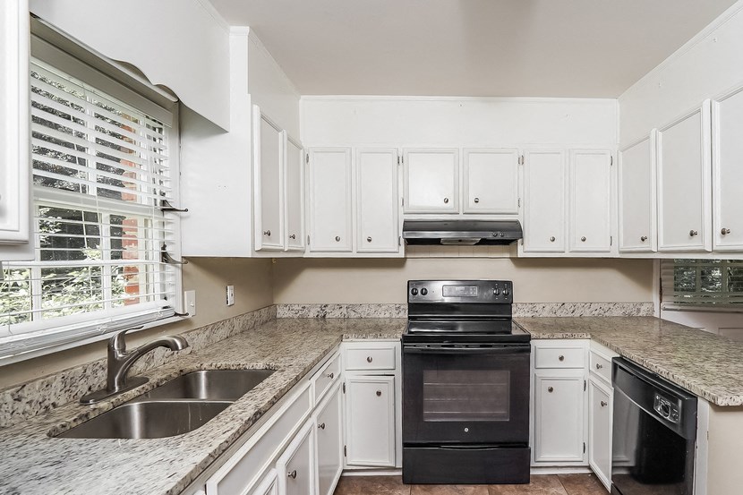 a kitchen with white cabinets and a sink and black appliances