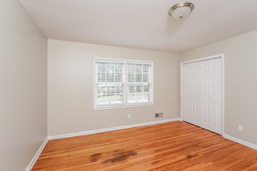 an empty bedroom with wood floors and a white door