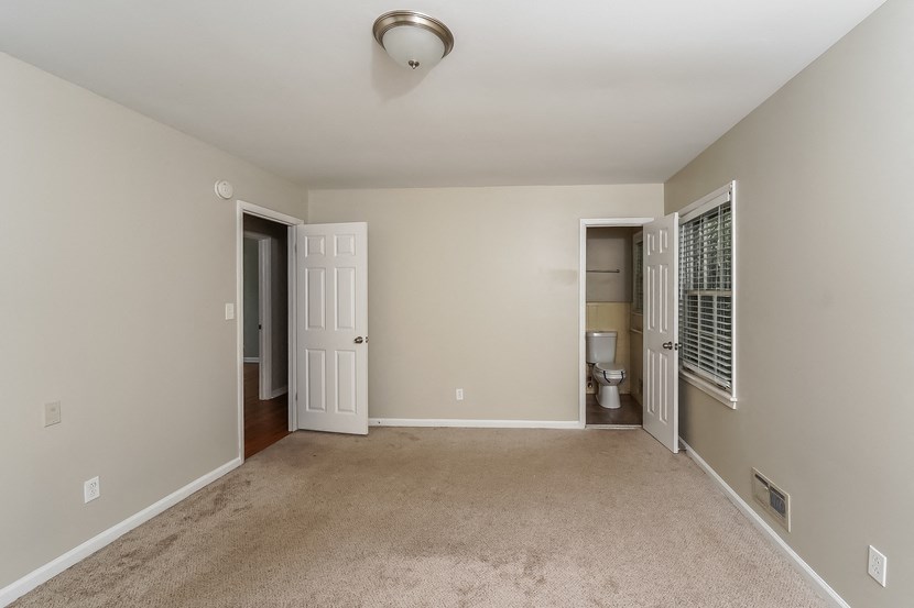a spacious living room with carpet and a door to the bathroom