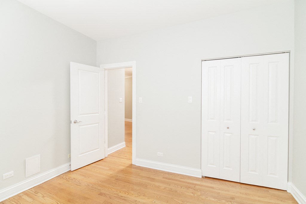 an empty room with white doors and a wood floor
