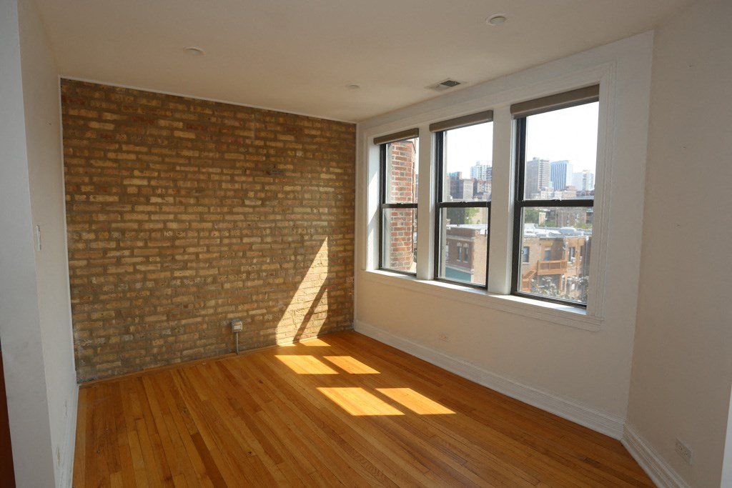 an empty living room with a brick wall and wooden floors