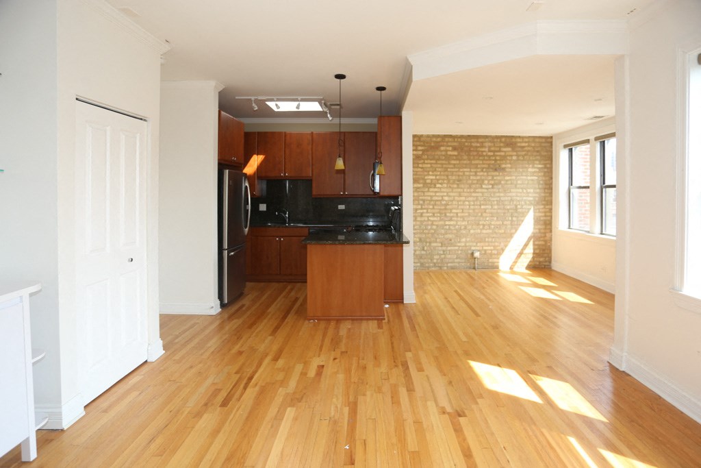an empty living room and kitchen with wood flooring and black appliances