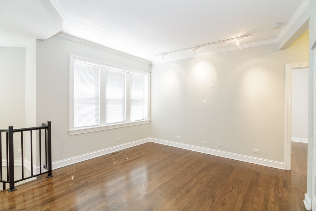 an empty living room with a hardwood floor and a window