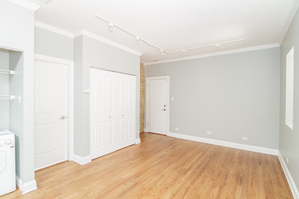 an empty living room with white doors and a wood floor