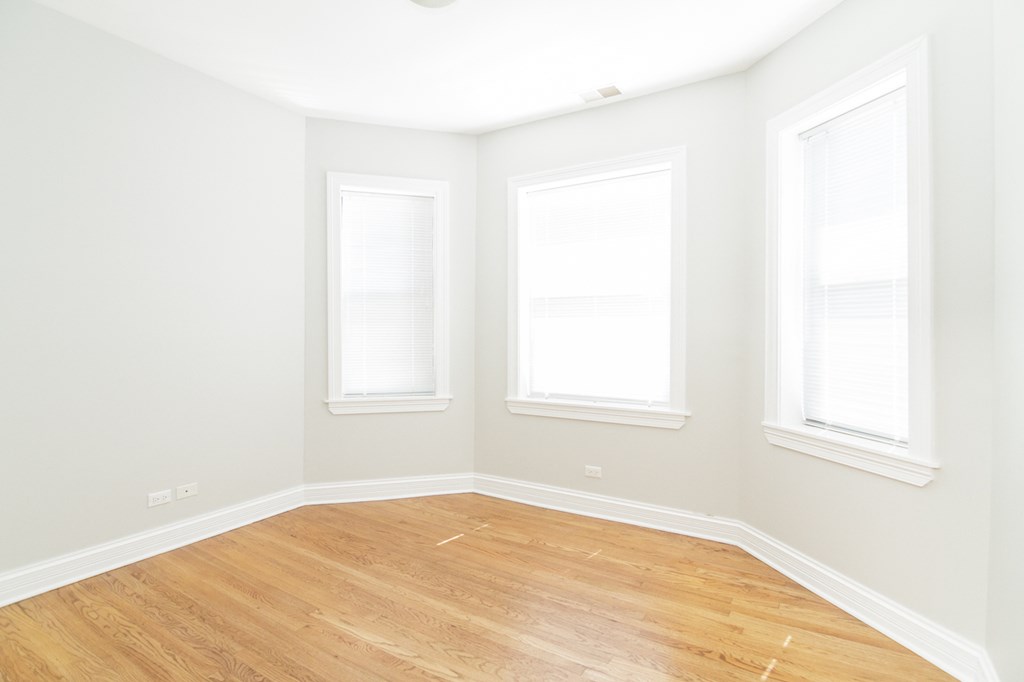 an empty room with three windows and a wooden floor