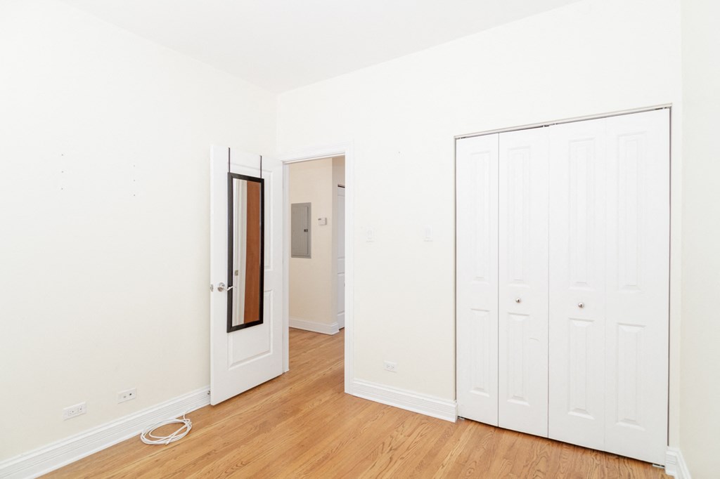 a bedroom with white walls and a door to a closet