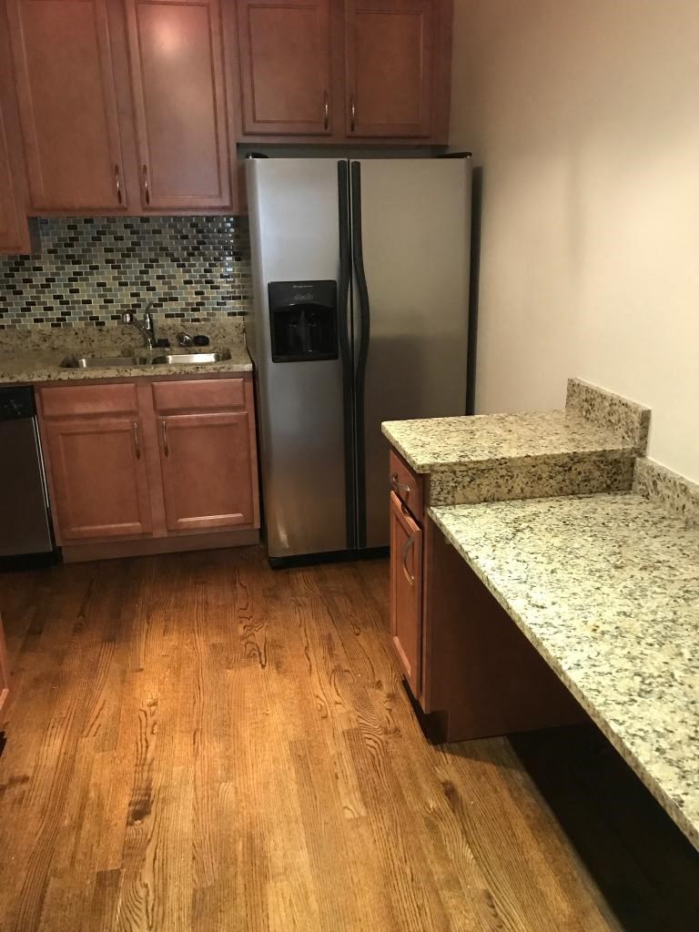 a kitchen with a stainless steel refrigerator and wooden floors